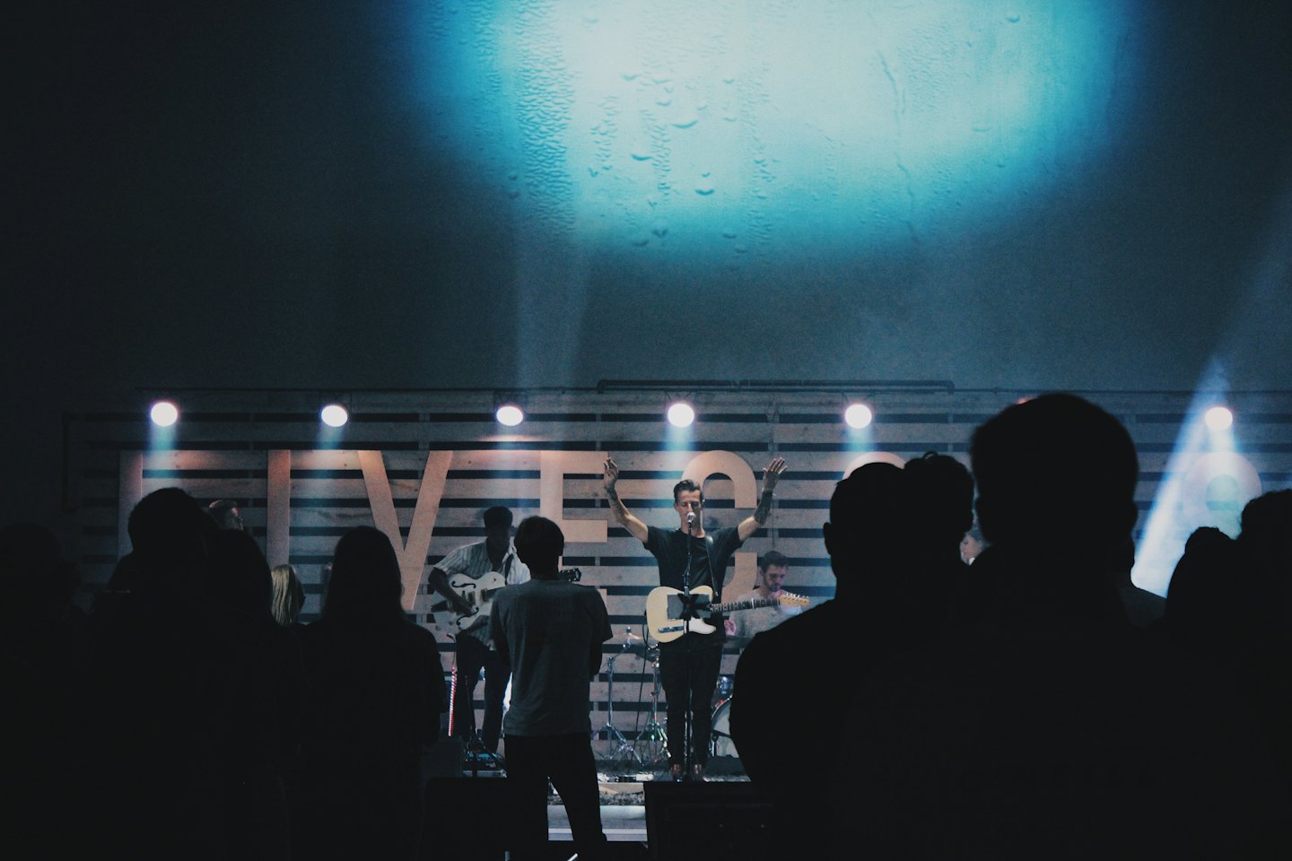 A singer performs on stage with his band members.