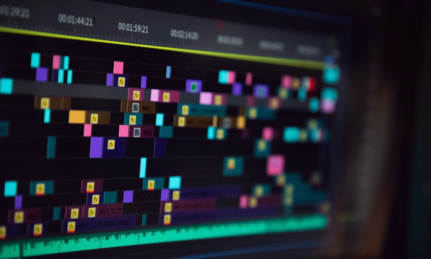 Video editing timeline with colorful clips and time codes on a screen.